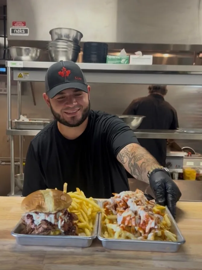 Nick serving a burger, fries, and loaded fries from the kitchen window